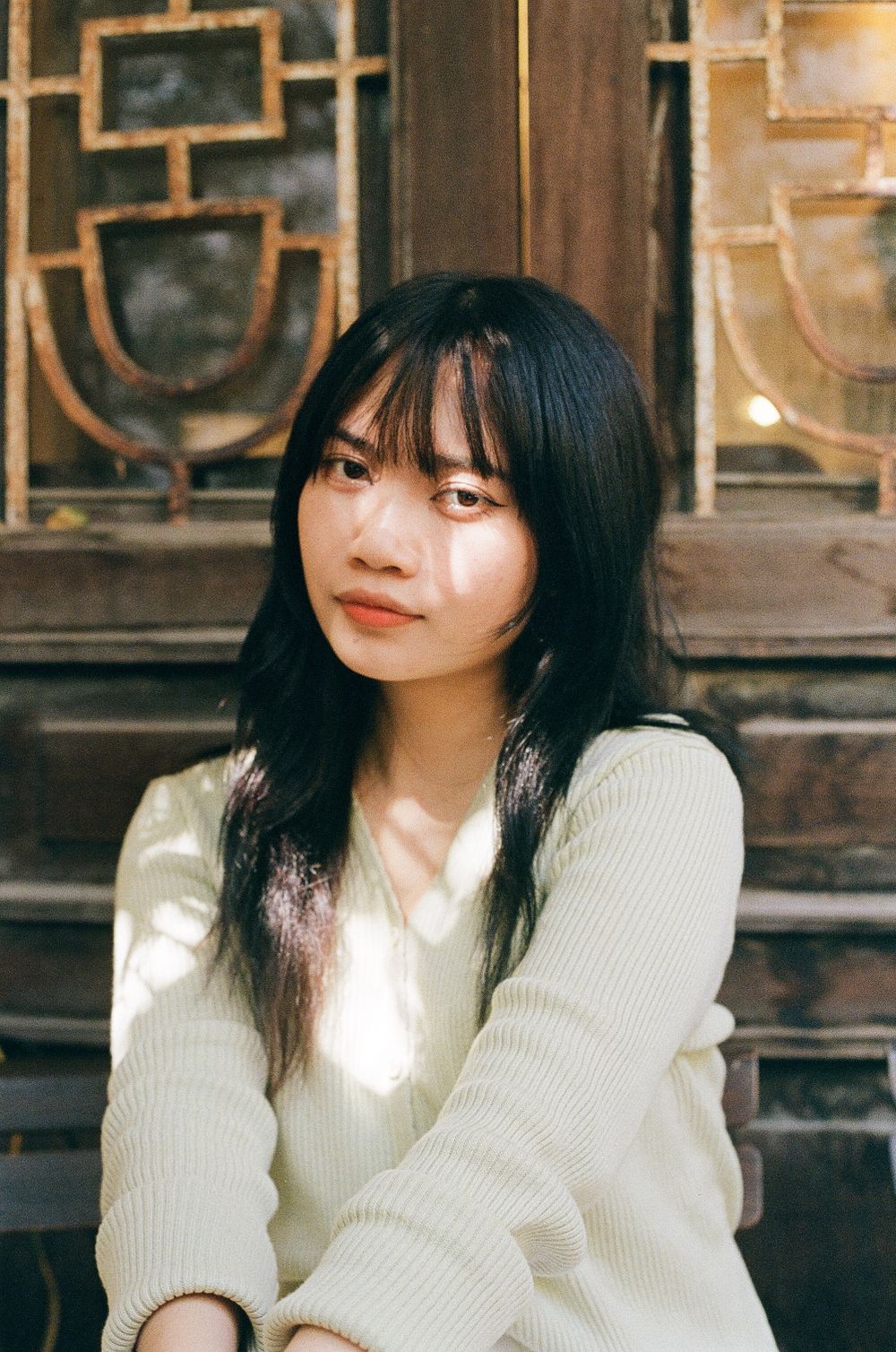 白いニットを着て古い建物の前に座る女性