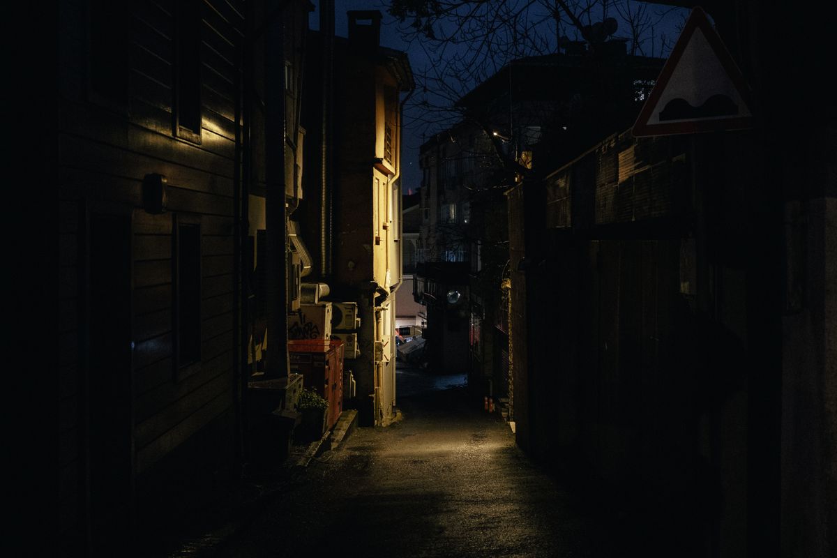 暖色の灯りが残る暗い路地