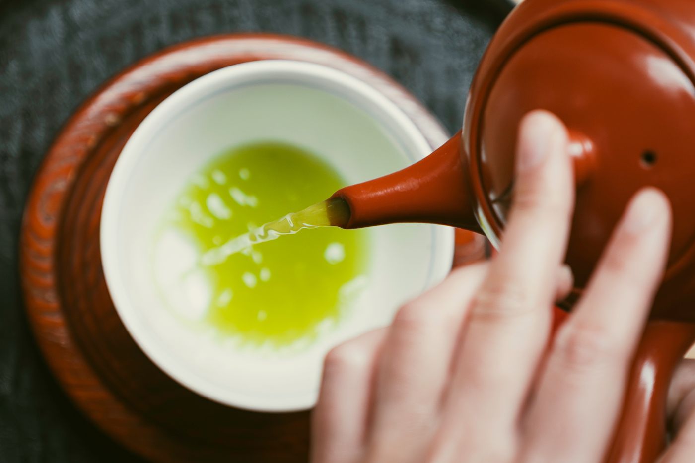 急須から白い碗に緑茶を注ぐ手元